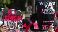 Massa membawa poster bertuliskan 'Stop Genocide' dan 'We Stand With Uyghur' saat menggelar aksi Solidaritas untuk Muslim Uighur di depan Kedutaan Besar China di Jakarta, Jumat (20/12/2019). Mereka mengecam dan mengutuk keras penindasan terhadap muslim Uighur di China. (Liputan6.com/Faizal Fanani)