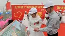 Pengantin pria memperlihatkan rancangan bandara pada pengantin wanitanya, Beijing, Senin (12/12). Kelima pekerja ini kompak untuk menggelar upacara pernikahan di tempat proyek mereka bekerja yaitu sebuah bandara. (AFP PHOTO)