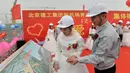 Pengantin pria memperlihatkan rancangan bandara pada pengantin wanitanya, Beijing, Senin (12/12). Kelima pekerja ini kompak untuk menggelar upacara pernikahan di tempat proyek mereka bekerja yaitu sebuah bandara. (AFP PHOTO)