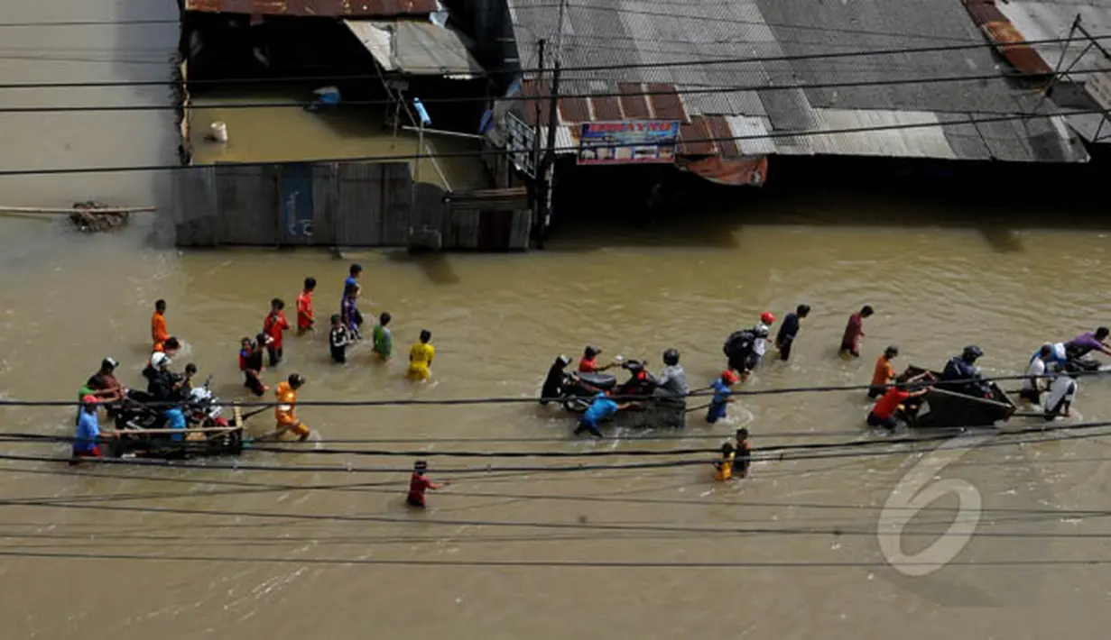 Pengendara motor menggunakan jasa gerobak untuk melewati banjir yang menggenangi Jalan KH Hasyim Ashari, Ciledug, Kota Tangerang, Selasa (10/2/2015). (Liputan6.com/Andrian M Tunay)