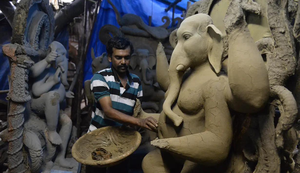 Seorang seniman India menyelesaikan pembuatan patung Dewa Hindu, Lord Ganesh di sebuah lokakarya di Hyderabad (19/8/2019). Patung ini dibuat dengan bahan-bahan ekologis untuk mengurangi polusi selama perendaman untuk festival Ganesh Chaturthi. (AFP Photo/Noah Seelam)