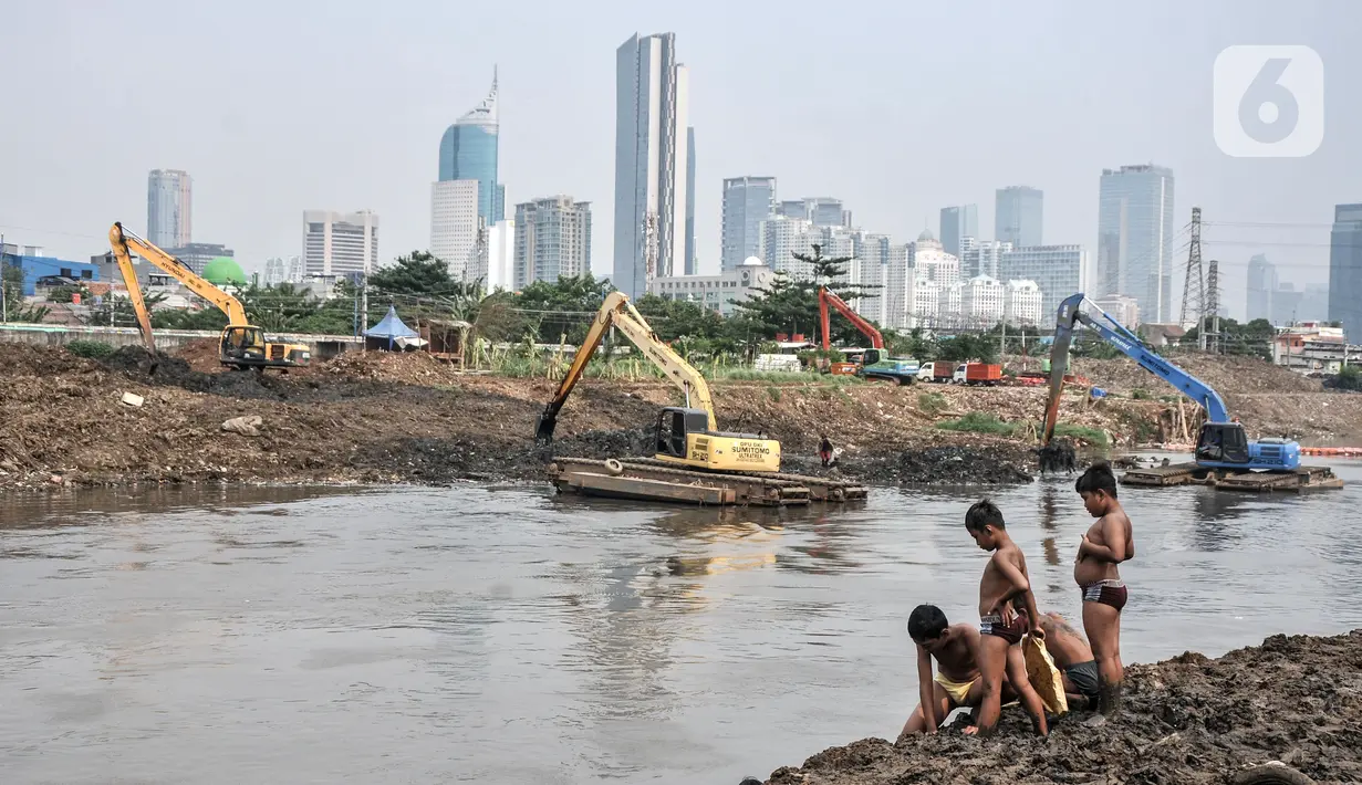 Anak-anak bermain dekat alat berat yang tengah mengerjakan pengerukan lumpur di Kali Ciliwung Segmen Kanal Banjir Barat (KBB), Tanah Abang, Kamis (30/9/2021). Gerebek Lumpur dilakukan secara serentak di lima wilayah Ibu Kota. (merdeka.com/Iqbal S. Nugroho)