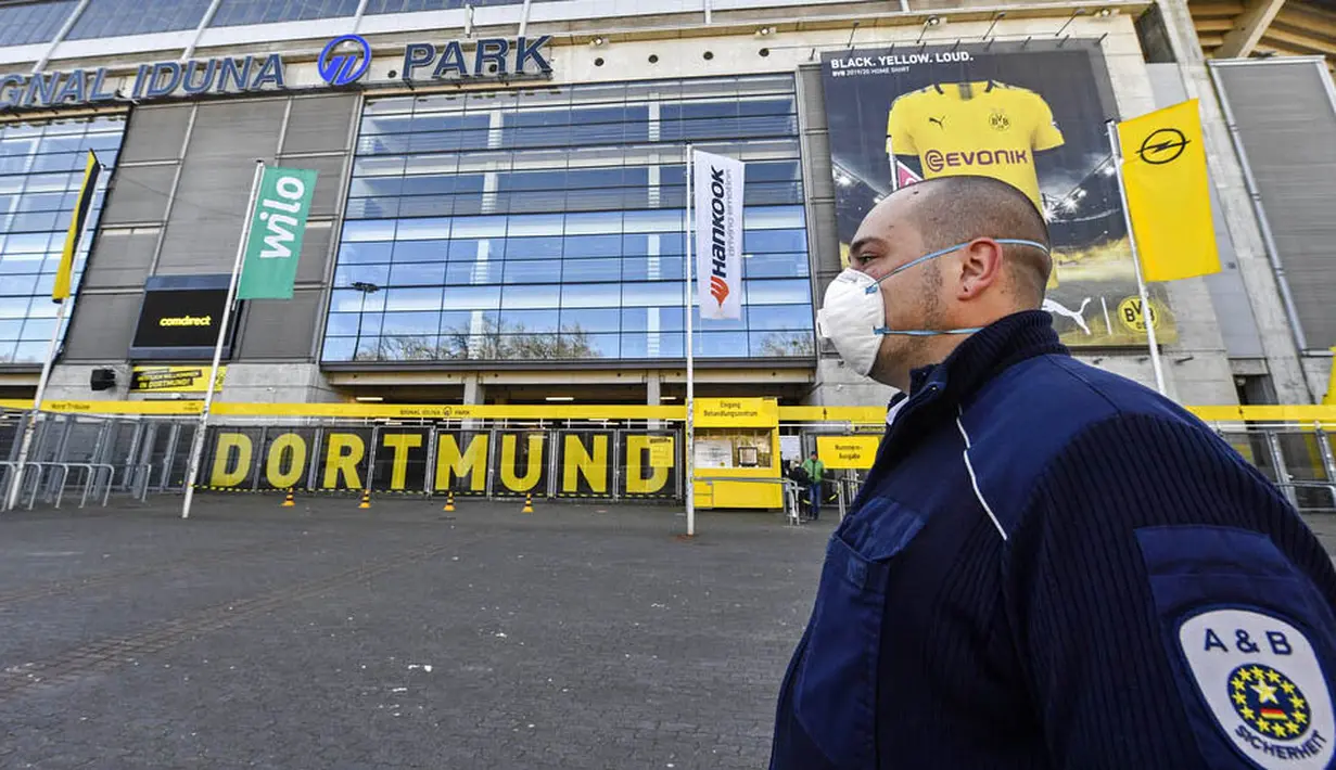 Petugas Keamanan dengan menggunakan masker berjaga di depan Stadion Signal Iduna Park, Jerman, Sabtu (4/4/2020). Stadion Borussia Dortmund ini dialihfungsikan menjadi tempat pusat pengujian COVID-19. (AP/Martin Meissner)