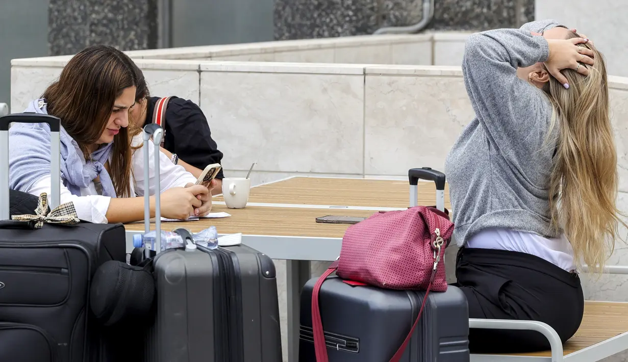 Dua perempuan menunggu dengan barang bawaan mereka di ruang keberangkatan di bandara internasional Brussel selama pemogokan nasional di Brussels, Belgia, Senin (20/6/2022). Serikat pekerja mengatakan 80.000 orang mengambil bagian dalam pemogokan nasional Senin, yang mengganggu rute transportasi di ibu kota Belgia sepanjang hari. (AP Photo/Olivier Matthys)