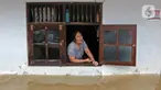 Warga melihat keluar jendela saat banjir di RW 07, Kelurahan Pekayon, Jakarta Timur, Sabtu (20/2/2021). Banjir di kawasan tersebut terjadi akibat curah hujan yang tinggi. (Liputan6.com/Herman Zakharia)