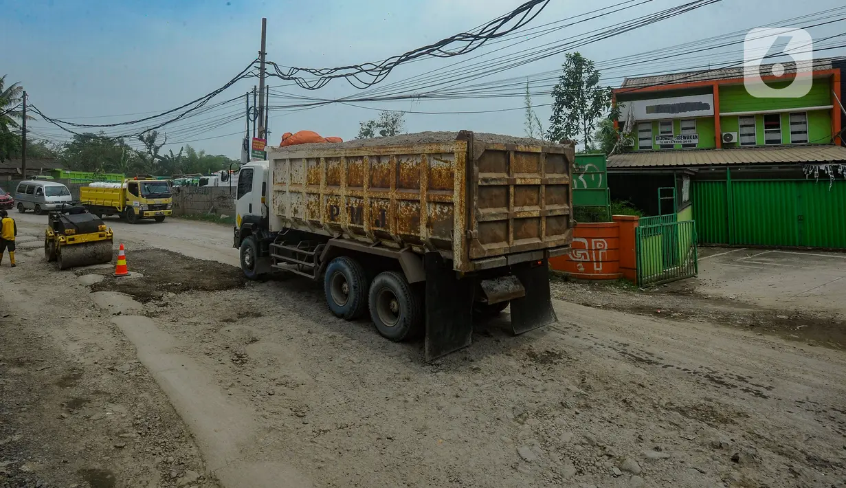 Petugas melakukan penambalan jalan berlubang di Jalan Muhammad Toha, Parung Panjang, Bogor, Jawa Barat, Rabu (22/11/2023). (merdeka.com/Arie Basuki)