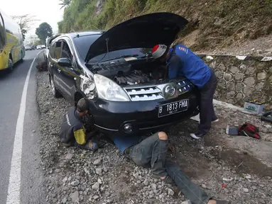 Montir memperbaiki mobil yang rusak di Jalan Warung Peuteuy, Garut, Jabar, Senin (4/7). Banyaknya kendaraan pemudik yang rusak menjadi berkah bagi para montir panggilan dengan pendapatan hingga 4x lipat dibanding biasa. (Liputan6.com/Immanuel Antonius)