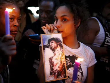 Sejumlah penggemar menyalakan lilin untuk penghormatan bagi musisi legendaris dunia, Prince di Taman Leimert, Los Angeles, Kamis (21/4). Prince ditemukan tak bernyawa di dalam lift di komplek tempat tinggalnya di Paisley Park. (REUTERS/Lucy Nicholson)