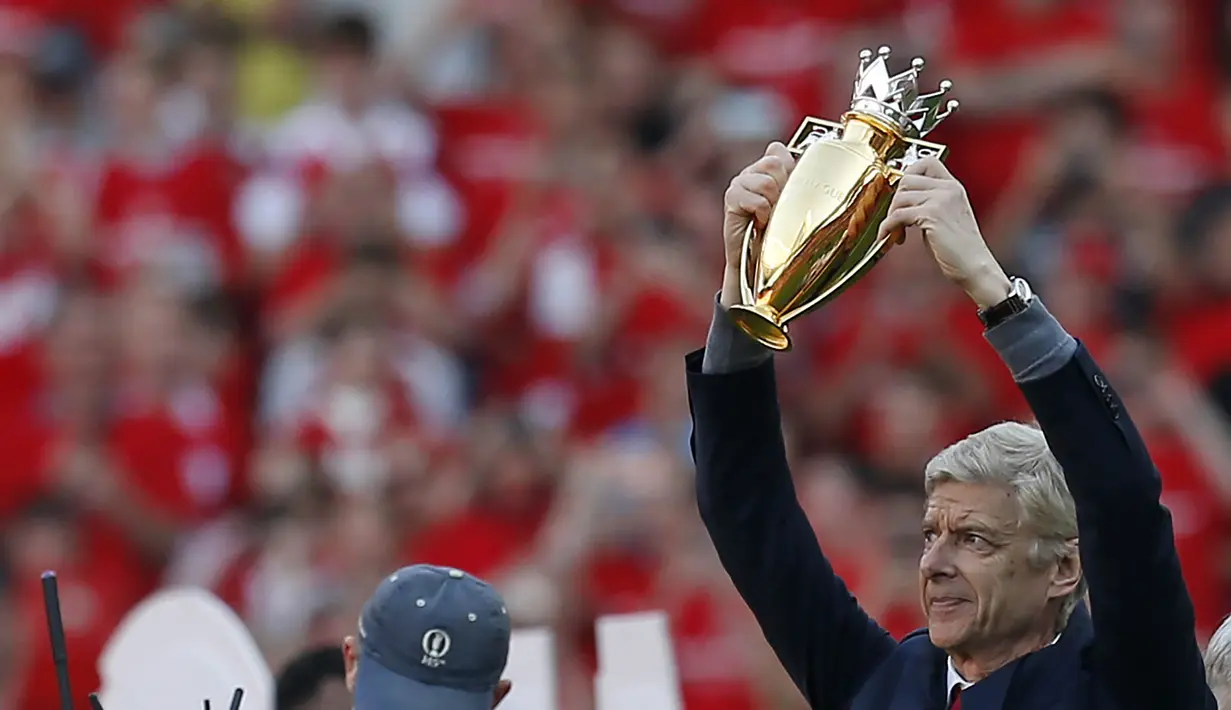 Pelatih Arsenal, Arsene Wenger, mengangkat trofi mini  saat perpisahan di Stadion Emirates (6/5/2018). Selama 22 tahun membesut Arsenal, Wenger telah mempersembahkan 17 gelar dan 704 Kemenangan. (AFP/Ian Kington)