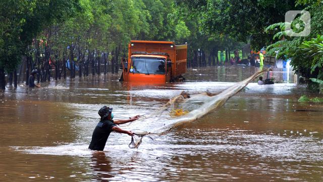 FOTO: Warga Jala Ikan di Tengah Jalan yang Terendam Banjir