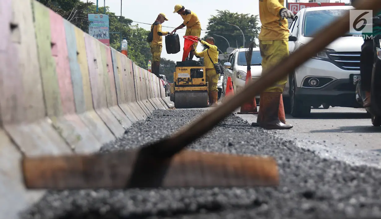 Petugas Bina Marga Pasar Minggu menambal jalan yang rusak di Jalan Raya Ragunan, Jakarta, Senin (22/4). Petugas mengaku bahwa keberadaan beton pembatas jalan justru membuat jalan di kawasan tersebut selalu rusak setiap hujan deras karena menimbulkan genangan air. (Liputan6.com/Immanuel Antonius)