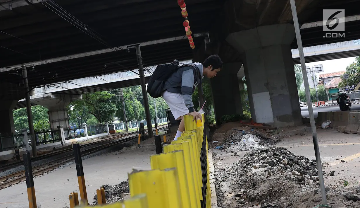 Seorang siswa melewati pagar perlintasan kereta api di kawasan Tanjung Barat, Jakarta, Senin (7/1). Sejumlah pejalan kaki tetap memilih untuk melompati pagar pembatas dari pada menggunakan fasilitas JPO. (Liputan6.com/Immanuel Antonius)