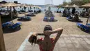 Seorang wanita mandi di pantai Desa Lagonissi, beberapa mil barat daya Athena, Yunani, Kamis (29/7/2021). Gelombang panas membuat orang-orang berbondong-bondong ke pantai, air mancur umum, dan lokasi ber-AC. (AP Photo/Yorgos Karahalis)
