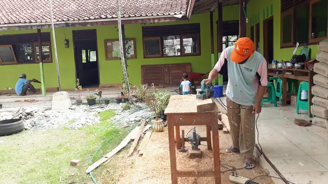 Seorang pekerja tengah membuat kusen sekat kelas Madrasah Diniyah I Cingebul, Lumbir, Banyumas yang sudah rusak dan lapuk. (Foto: Liputan6.com/Muhamad Ridlo)