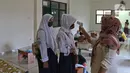 Siswa dicek suhu tubuh saat belajar di Aula Kelurahan Jatirahayu, Bekasi, Jawa Barat, Rabu (29/7/2020). Pemerintah Kota Bekasi melalui Kelurahan Jatirahayu menyediakan fasilitas wifi gratis bagi siswa yang terkendala kuota internet dalam kegiatan belajar secara daring. (Liputan6.com/Herman Zakharia)