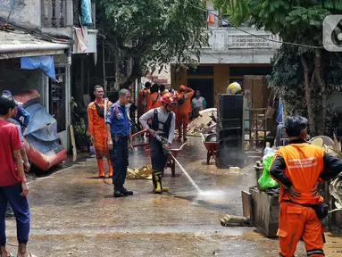 Personel dari Dinas Penanggulangan Kebakaran dan Penyelamatan (Gulkarmat) Provinsi DK Jakarta menyemprotkan air untuk membersihkan endapan sisa lumpur di permukiman warga di kawasan Rawajati, Kalibata, Jakarta Selatan, Jakarta, Rabu (5/3/2025). (Liputan6.com/Angga Yuniar)