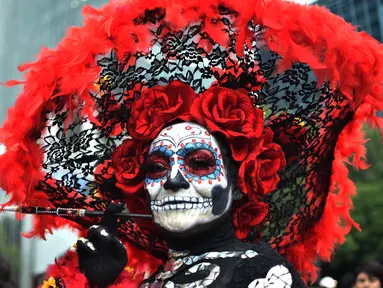 Seorang wanita berpakaian seperti "Catrina" ambil bagian dalam parade catrinas atau Hari Orang Mati di Reforma Avenue, Mexico City, 21 Oktober 2018. Hari kematian ini merupakan tradisi Halloween ala warga Hispanik di Meksiko. (RODRIGO ARANGUA/AFP)