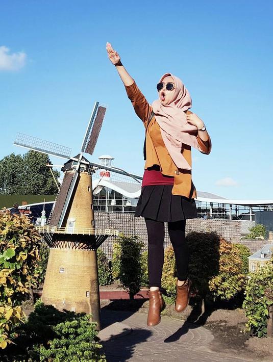 Gadis kelahiran tahun 1995 ini terlihat bahagia saat liburan ke Belanda. Menggunakan pakaian padu padan warna cokelat dan hitam, ditambah dengan hijab berwarna krem membuat penampilannya semakin mengagumkan. Posenya selalu ceria. (Liputan6.com/IG/@riaricis1795)