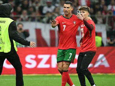 Seorang steward berlari untuk mengusir salah satu suporter yang masuk ke lapangan untuk berswafoto dengan pemain bintang, Cristiano Ronaldo selama pertandingan sepak bola UEFA Nations League 2024/2025, Liga A Grup A1 Polandia vs Portugal di Stadion PGE Narodowy, Warsawa, Polandia pada Sabtu 12 Oktober 2024 atau Minggu (13/10/2024) dini hari WIB. (Sergei GAPON/AFP)