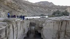 Warga Israel menyaksikan banjir bandang terjadi menyusul hujan lebat di gurun Negev di sebelah timur kota Dimona Israel pada 26 Desember 2022. Hujan lebat mengguyur Israel pada hari Senin (26/12) membanjiri jalan-jalan kota, memicu banjir bandang di dasar sungai gurun yang kering dan membasahi daerah pedesaan karena suhu turun ke level terendah musim ini. (AFP/Menahem Kahana)