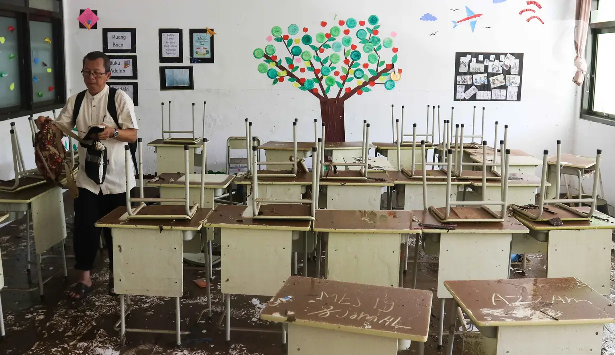 Petugas membawa barang-barang saat membersihkan ruangan di MTsN 19 Pondok Labu, Jakarta, Jumat (7/10/2022). Petugas PPSU, Satpol PP, dan Dinas Pemadam Kebakaran membersihkan ruang kelas, kantin, dan fasilitas lainnya usai terendam banjir pada Kamis sore kemarin. (Liputan6.com/Herman Zakharia)