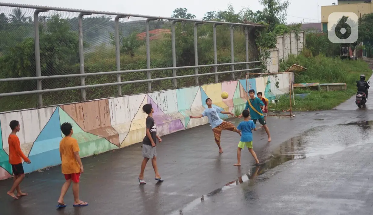 Anak-anak bermain sepak bola di sekitar kawasan Depok, Jawa Barat, Kamis (16/4/2020). Kurangnya sanksi tegas membuat sebagian warga Depok bebas berkeliaran untuk bersosialisasi, meskipun saat ini sedang diberlakukan PSBB untuk mencegah penyebaran Covid-19. (Liputan6.com/Immanuel Antonius)