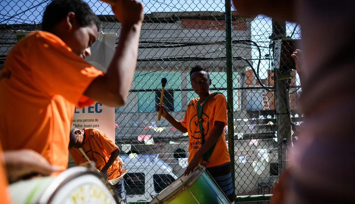 Anak-anak melakukan atraksi manabuh drum band pada program Volleyball Development Training yang digagas oleh Federasi Bola Voli Internasional di Formiga favela, Rio de Janeiro, (2/8/2016). (AFP/Leon Neal)
