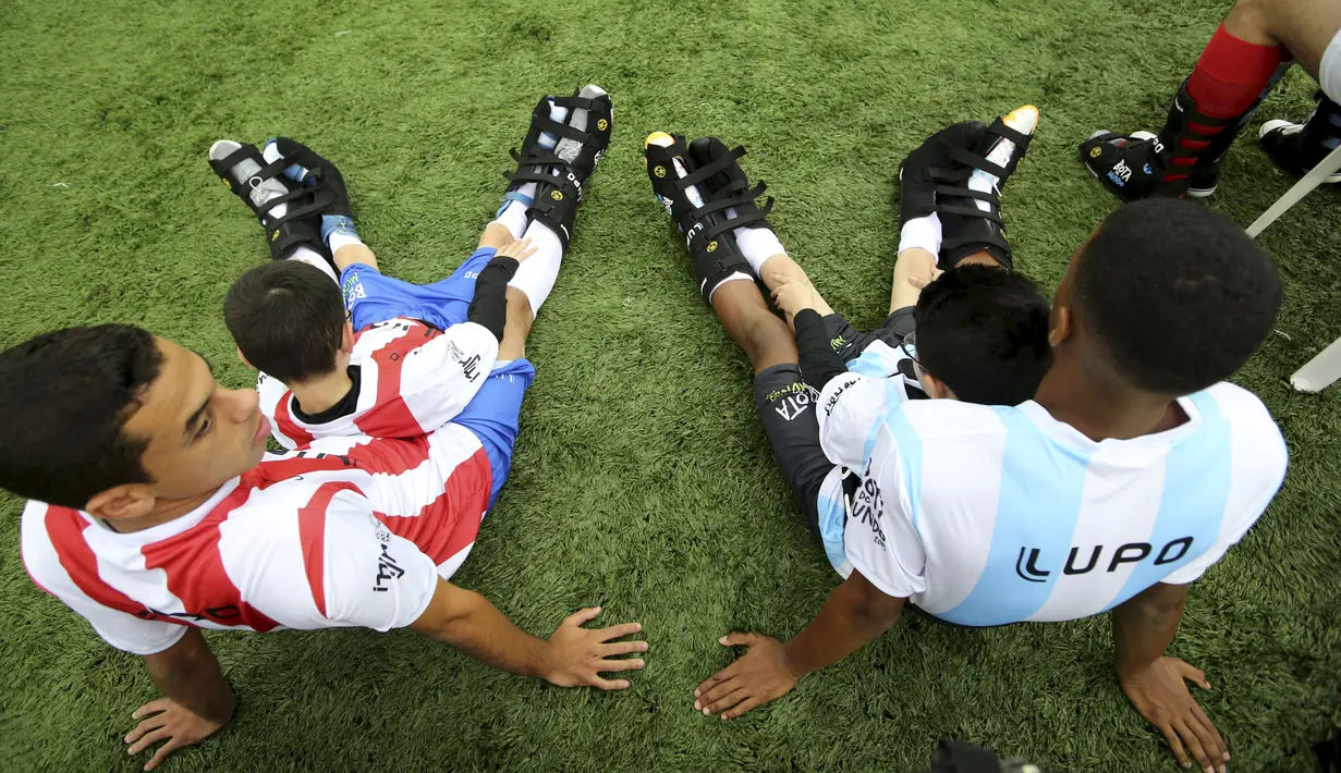 Sejumlah anak berkebutuhan khusus dan pesepakbola Brasil duduk di lapangan saat acara "World Boots" di Neymar Institute, Brasil, 7 Juni 2015. Acara tersebut diadakan pesepakbola Brasil Neymar untuk anak-anak berkebutuhan khusus. (REUTERS/Paulo Whitaker)