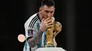 Kapten dan penyerang Argentina, Lionel Messi mencium Trofi Piala Dunia 2022 selama setelah Argentina memenangkan pertandingan final Piala Dunia Qatar 2022 melawan Prancis di Stadion Lusail di Lusail, utara Doha (18/12/2022). Argentina menang atas Prancis lewat adu penalti. Ini merupakan gelar pertama Messi di Piala Dunia. (AFP/Paul Ellis)