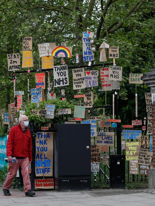 Seorang pria berjalan melewati kumpulan plakat yang dirancang oleh seniman lokal Peter Liversidge untuk mendukung Layanan Kesehatan Nasional (National Health Service/NHS) di London, Inggris, (29/4/2020). (Xinhua/Han Yan)