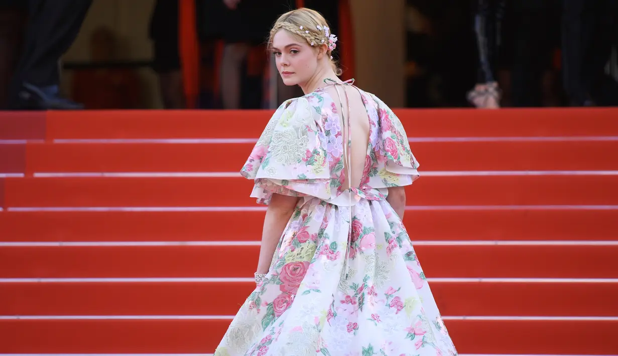 Elle Fanning menaiki tangga karpet merah saat tiba menghadiri screening film "Les Miserables" dalam acara Festival Film Cannes ke-72 di Prancis (15/5/2019). Aktris 21 tahun ini tampil cantik mengenakan gaun taman haute couture karya Valentino. (AP Photo/Arthur Mola)