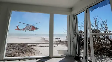 Helikopter Penjaga Pantai AS terlihat lepas landas dari dalam rumah yang rusak akibat Badai Ian di Pulau Sanibel, Florida, 30 September 2022. Badai Ian tengah jadi sorotan di AS, sebab terjangannya begitu dahsyat hingga meninggalkan jejak kerusakan dan korban jiwa. (AP Photo/Steve Helber)