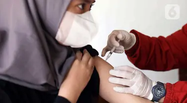 Petugas kesehatan dari Puskesmas Kecamatan Matraman melakukan vaksinasi COVID-19 di SD Negeri 25 Utan Kayu Selatan, Matraman, Jakarta Timur, Rabu (23/3/2022). Layanan vaksinasi digelar setiap hari Senin sampai Jumat pukul 08.00-11.00 WIB. (Liputan6.com/Herman Zakharia)