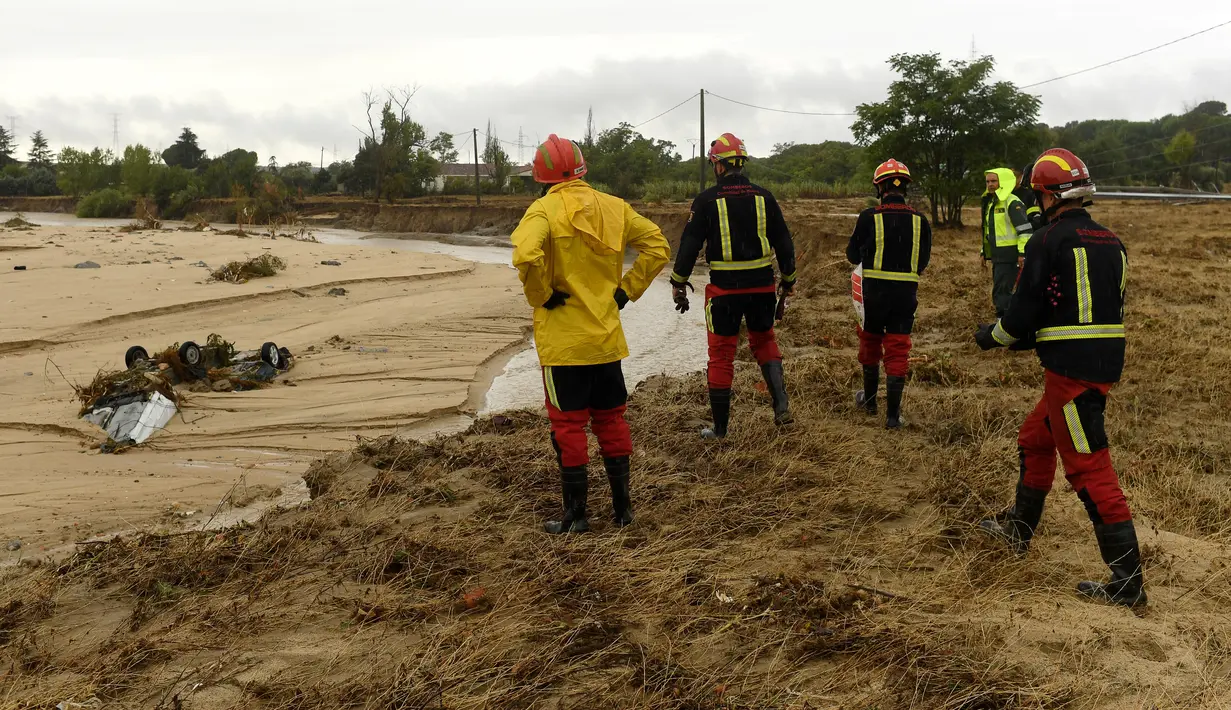 Petugas pemadam kebakaran melihat mobil-mobil yang terdampar di tepi sungai di kota Aldea del Fresno, di wilayah Madrid, Spanyol, Senin (4/9/2023). (Oscar DEL POZO CAÑAS / AFP)