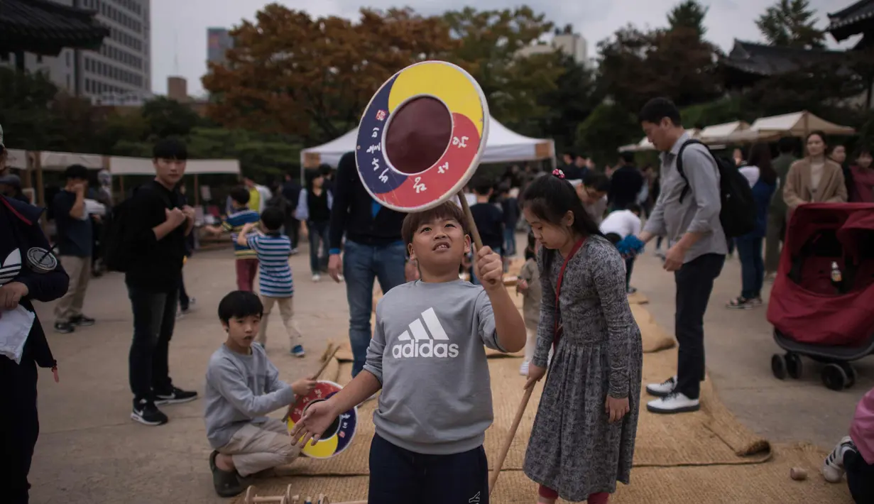  Seorang anak memainkan permainan tradisional selama perayaan Chuseok di Seoul (5/10). Seperti halnya kebanyakan festival panen lainnya di seluruh dunia, Chuseok dirayakan sekitar ekuinoks musim gugur. (AFP Photo/Ed Jones)