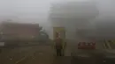 Seorang pengemudi berdiri di samping truknya saat menunggu pembukaan jalan raya yang ditutup karena kabut tebal di Lahore, Pakistan, 15 Desember 2021. Kabut tebal membuat kendaraan harus melaju lambat karena jarak pandang berkurang. (AP Photo/K.M. Chaudary)