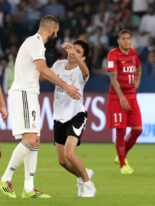 Fans berusaha memeluk striker Real Madrid, Karim Benzema di semifinal Piala Dunia Antarklub 2018 antara Real Madrid vs Kashima Antlers di stadion Zayed Sports City, Uni Emirat Arab (19/12). Di pertandigan ini Madrid menang 3-1.(AFP Photo/Giuseppe Cacace)