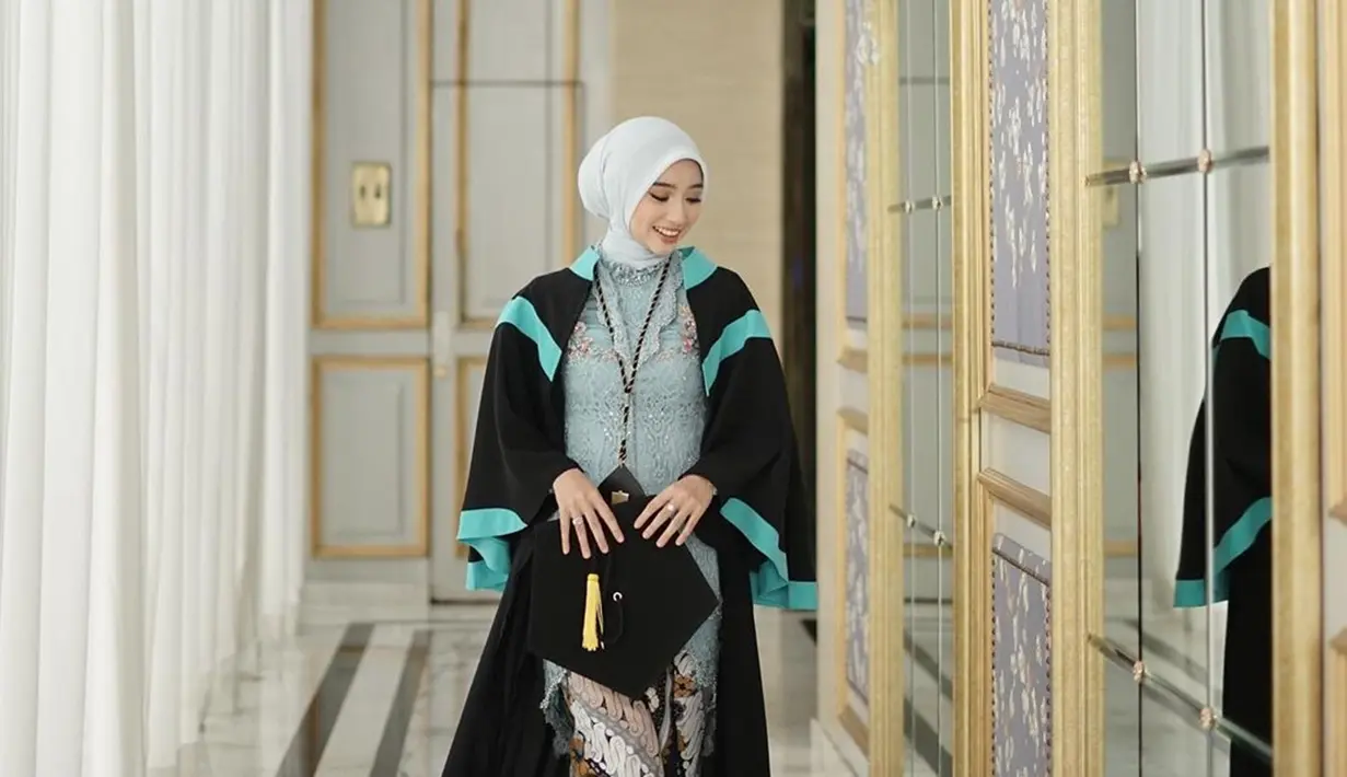 Kebaya biru Ansel dipadukan dengan kain batik dengan perpaaduan warna putih, cokelat muda, dan cokelat tua. Pakai atribut wisuda lengkap mulai dari jubah, toga dan medali, kebahagiaan terpancar jelas di wajah Ansellma Putri. Berpose candid sembari jalan, foto Ansellma ini dijepret dengan apik oleh fotografer. Lewat keterangan unggahannya, Ansel butuh dua hari untuk memilih foto. (Liputan6.com/IG/@ansellmaputri)