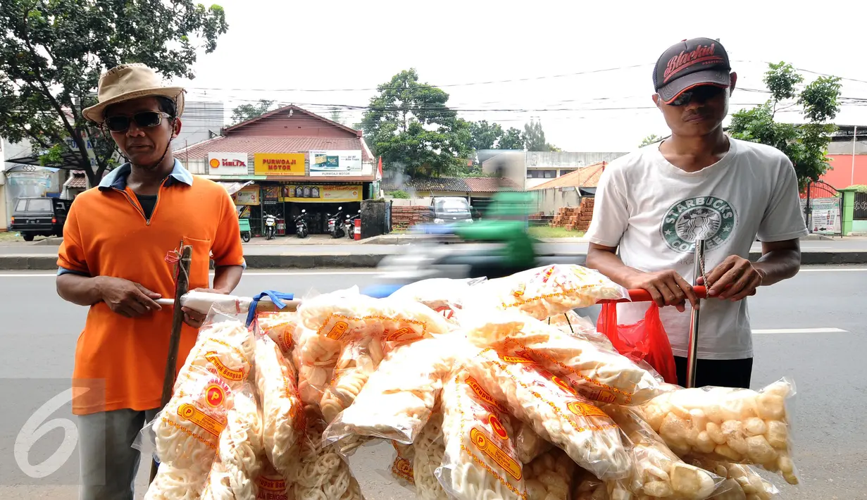 Iman (kiri) bersama Drajat berjalan berpose untuk Liputan6.com saat menjajakan kerupuk ikan di Jalan Raya Bogor, Depok, Jawa Barat, Rabu (19/10). Iman mengaku meski dalam keterbatasan ia tidak akan menyerah. (Liputan6.com/Helmi Fithriansyah)