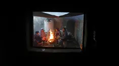 Sebuah keluarga duduk sekitar kayu bakar perapian rumah mereka saat cuaca dingin di daerah kumuh Kota Gaza, Palestina, 27 Januari 2022. (AP Photo/Hatem Moussa)