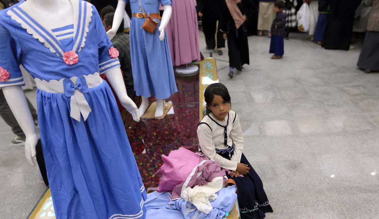Seorang gadis Yaman duduk dengan pakaian barunya di ruang pamer membagikan pakaian kepada anak-anak yang kehilangan orang tua dalam konflik, sebagai bagian dari kegiatan amal selama bulan suci Ramadhan, di ibu kota Sanaa (8/4/2022). (AFP/Mohammed Huwais)