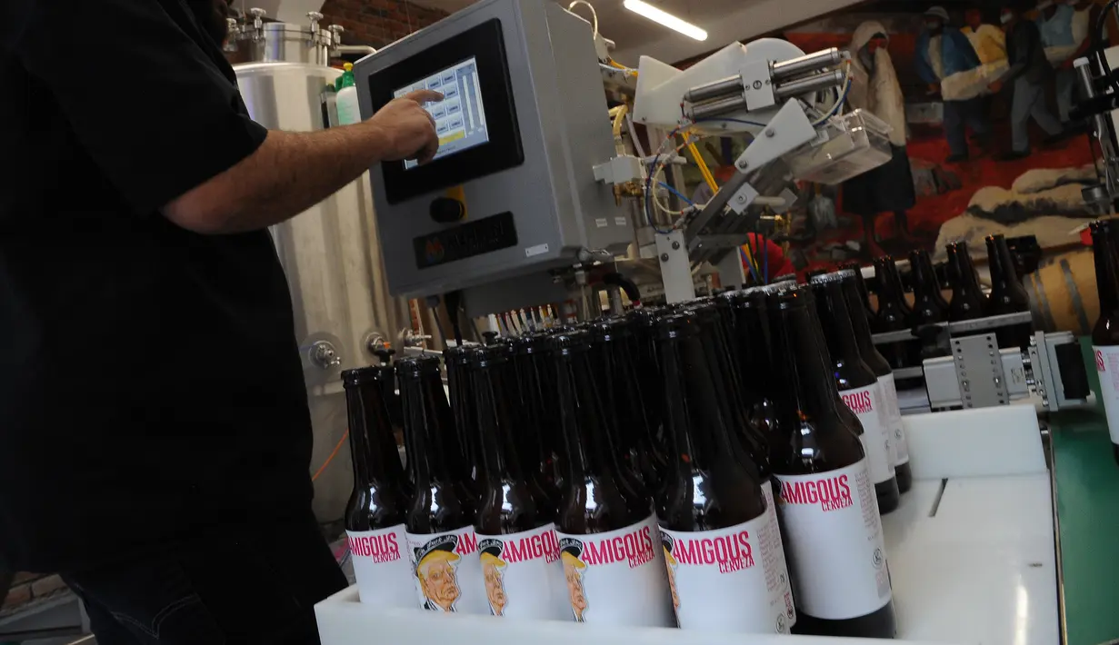 Pekerja memproses pembuatan bir dengan botol bergambar Presiden AS Donald Trump di perusahaan Cru Cru Brewery di Mexico City (15/6). Botol bir ini labelnya bergambar Donald Trump dengan mengenakan pakaian bergaya Mariachi.  (AFP Photo/Bernardo Montoya)