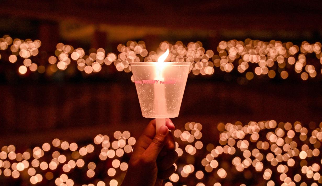Dari tema itu pula, banyak doa-doa yang dipanjatkan jemaat Gereja Bethany Nginden Surabaya di momen Natal tahun ini. Tampak dalam foto, seorang umat Kristiani memegang lilin selama misa Hari Natal di Gereja Bethany, Surabaya, Jawa Timur pada Kamis 25 Desember 2025. (JUNI KRISWANTO/AFP)