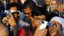 Warga menyaksikan fenomena Gerhana Matahari Total (GMT) menggunakan ponsel di halaman Taman Ismail Marzuki (TIM), Jakarta, Rabu (9/3). Fenomena gerhana matahari 90% bisa diamati selama 2,11 menit. (Liputan6.com/Fery Pradolo)