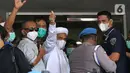 Rizieq Shihab (tengah) melambaikan tangan sesaat sebelum masuk gedung utama Mapolda Metro Jaya, Jakarta, Sabtu (12/12/2020). Rizieq Shihab akan menjalani pemeriksan sebagai tersangka penghasutan dan kerumunan di tengah pandemi Covid-19. (Liputan6.com/Helmi Fithriansyah)