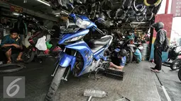 Seorang montir tengah memperbaiki mesin motor di kawasan Pasar Minggu, Jakarta, Kamis (30/6). Jelang mudik Lebaran menjadi rezeki tersendiri untuk pekerja jasa servis motor. (Liputan6.com/Yoppy Renato)