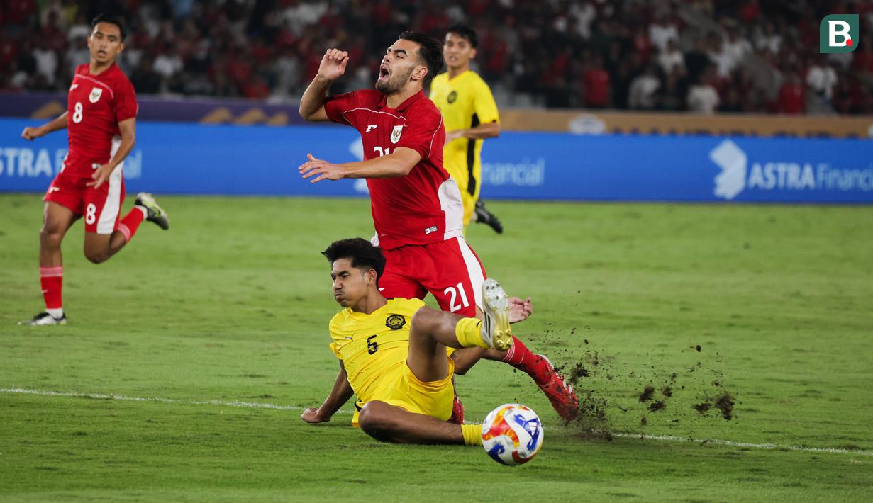Pemain belakang Malaysia berhasil merebut bola dari Jens Raven pada laga pemungkas Grup A Piala AFF U-23 2025, Senin (21/7/2025). (Bola.com/Abdul Aziz)
