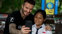 Mantan pesepakbola David Beckham berswafoto dengan siswi SMPN 17 Semarang, Sripun dalam kunjungannya sebagai Duta Kehormatan UNICEF ke Jawa Tengah, Rabu (28/3). Bersama Unicef, Beckham tengah melakukan kampanye anti-perundungan. (Liputan6.com/Pool/UNICEF)