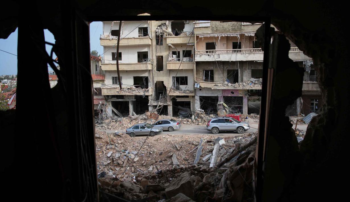 Kementerian Kesehatan Lebanon mencatat hingga Jumat 10 April 2026, secara keseluruhan 1.953 orang tewas dan 6.303 lainnya terluka sejak perang meletus antara Israel dan Hizbullah pada 2 Maret 2026. Tampak dalam foto, warga setempat melintas di lokasi bangunan yang hancur akibat serangan udara Israel, di Jibchit, Lebanon Selatan, Jumat, 17 April 2026, setelah gencatan senjata antara Israel dan Hizbullah. (AP Photo/Hassan Ammar)