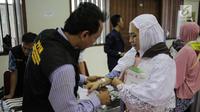 Panitia Penyelenggara Ibadah Haji (PPIH) memberikan gelang untuk calon jemaah haji kloter pertama di Asrama Haji, Jakarta, Sabtu (6/7/2019). Sebelum diberangkatkan, petugas mengecek kembali 385 calon jamaah untuk melakukan kelengkapan administrasi. (Liputan6.com/Faizal Fanani)